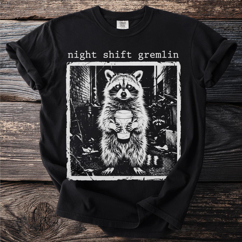 Black t-shirt with "night shift gremlin" text and raccoon holding coffee cup graphic.
