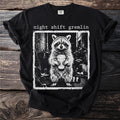Black t-shirt with "night shift gremlin" text and raccoon holding coffee cup graphic.