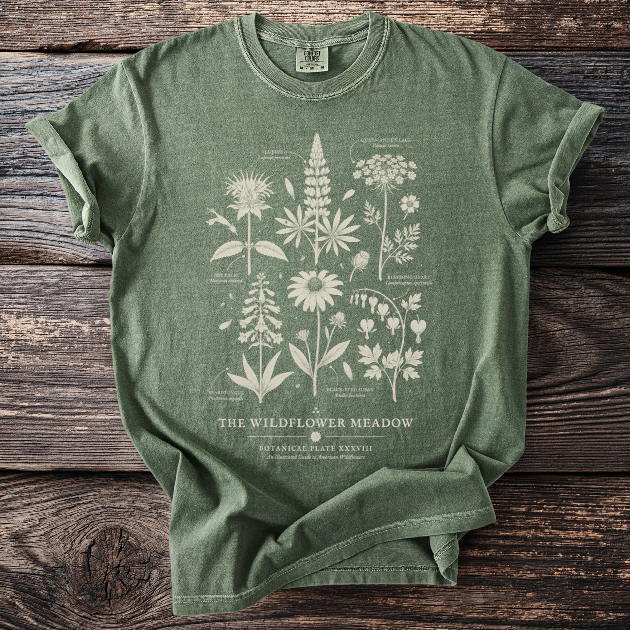 Green t-shirt with botanical illustration of "The Wildflower Meadow" and plant names.