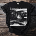 Black t-shirt with a distressed print of a possum under a car and text "do not perceive the creature".
