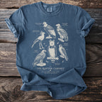Blue t-shirt with "The Raptor Cabinet" and illustrations of six birds of prey.