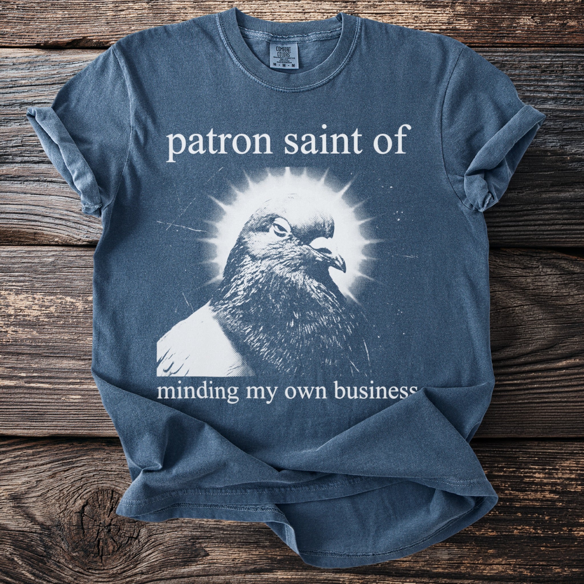 T-shirt with a pigeon graphic and text "patron saint of minding my own business."