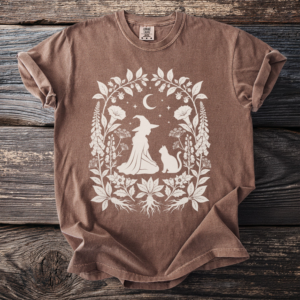 Brown t-shirt with white witch, cat, moon, and floral design.
