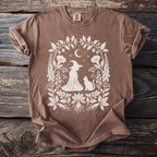 Brown t-shirt with white witch, cat, moon, and floral design.