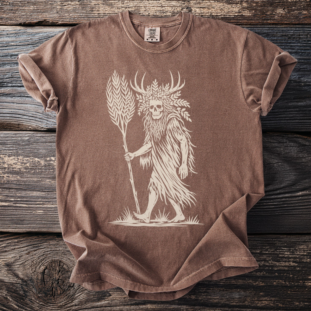 Brown t-shirt with a cream graphic of a skull-headed figure with antlers holding a stalk of wheat.