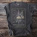T-shirt with botanical illustration of herbs labeled "Moonlit Apothecary Herbarium Plate I".