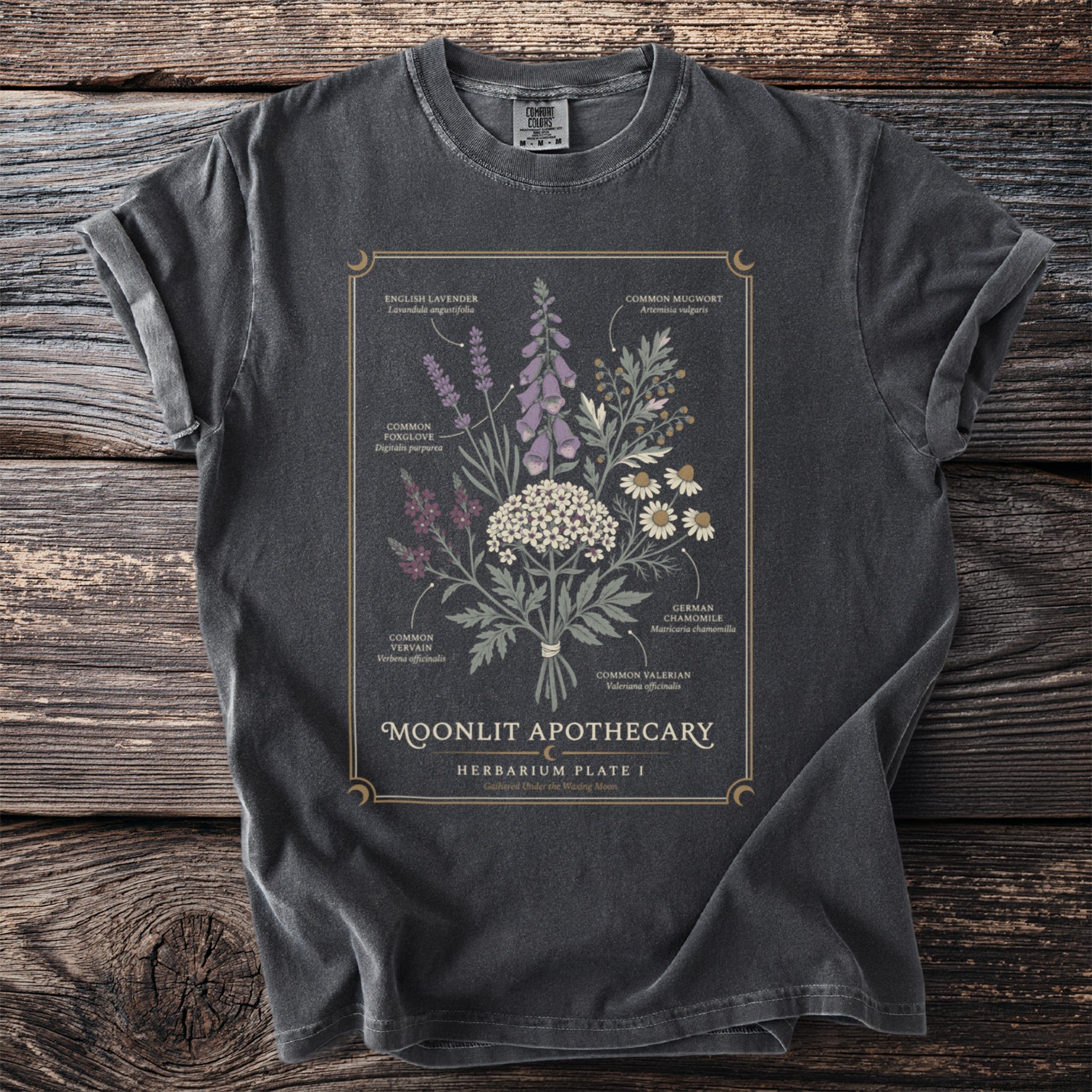 T-shirt with botanical illustration of herbs labeled "Moonlit Apothecary Herbarium Plate I".