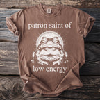 Brown t-shirt with a toad graphic and text reading "patron saint of low energy".