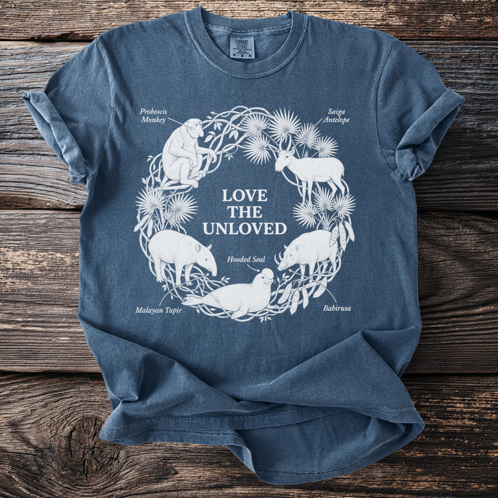 Blue t-shirt with white line drawing of endangered animals encircled by plants and the text "LOVE THE UNLOVED".
