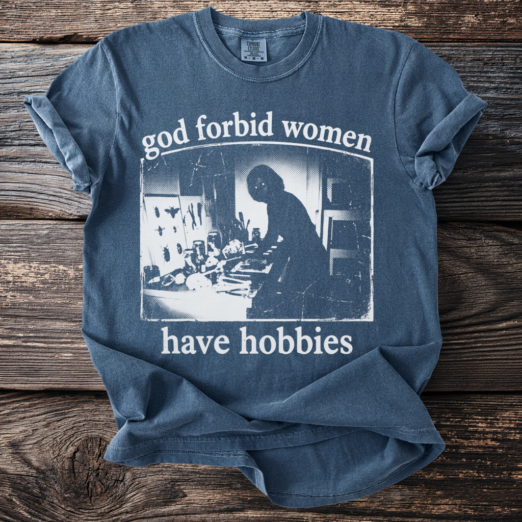 Blue t-shirt with distressed text "god forbid women have hobbies" and silhouetted image.