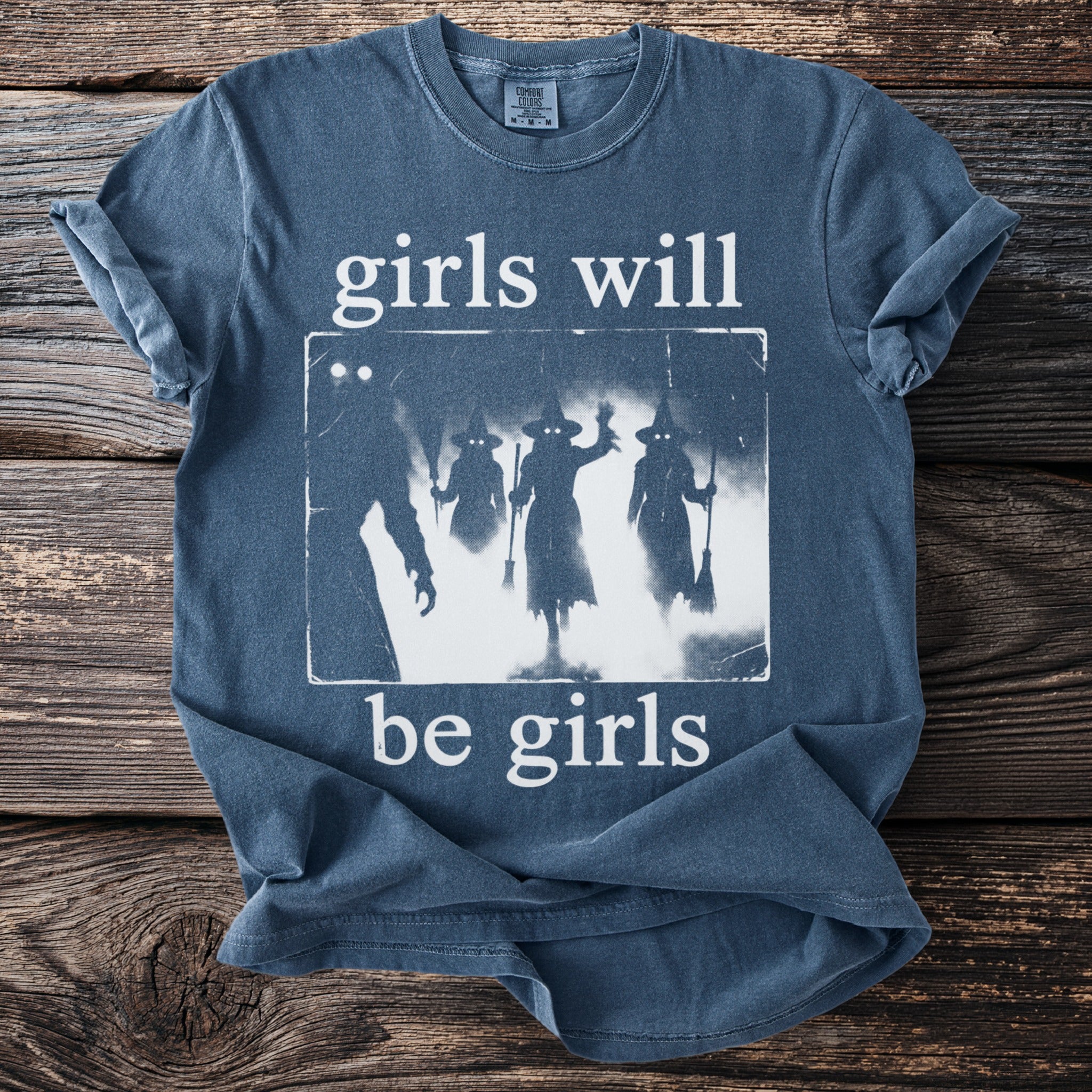 Blue t-shirt with graphic of witches and text "girls will be girls".