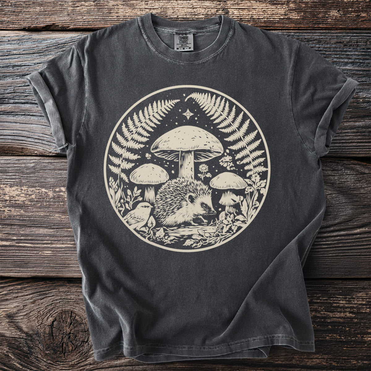 Dark grey t-shirt with a circular forest graphic featuring a hedgehog, bird, mushrooms, and ferns.
