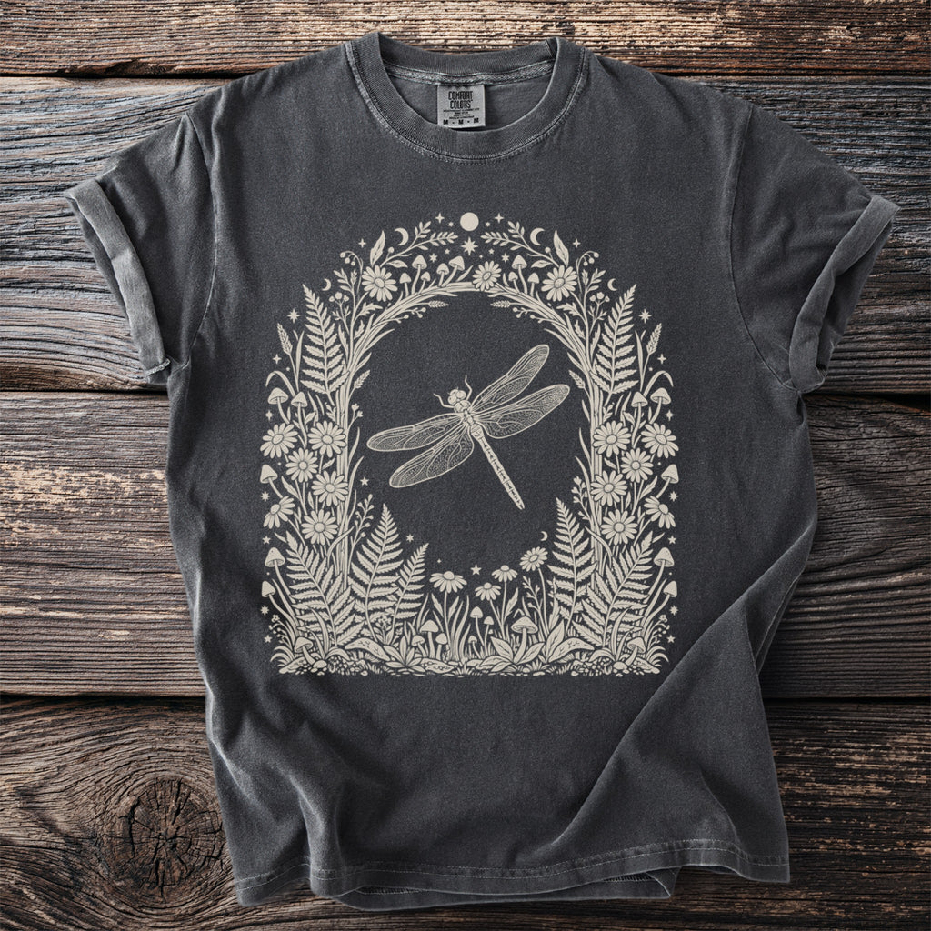 Dark gray t-shirt with a cream linework illustration of a dragonfly in a floral and mushroom arch.