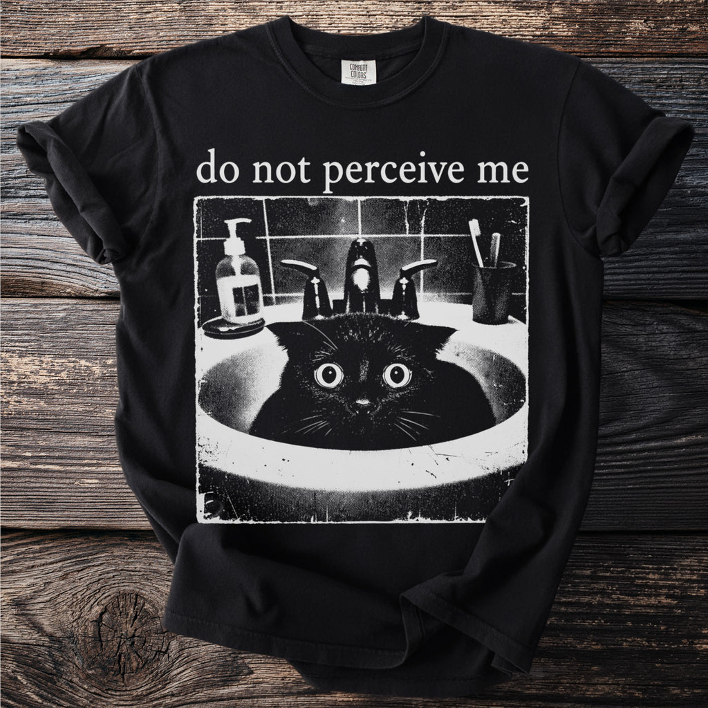 Black t-shirt with "do not perceive me" text and a distressed graphic of a startled black cat in a sink.