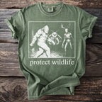 Green t-shirt with Bigfoot, moth, and skeleton deer graphic and "protect wildlife" text.