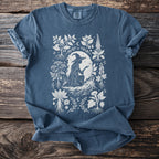 Blue t-shirt with white witch, plants and moon design.