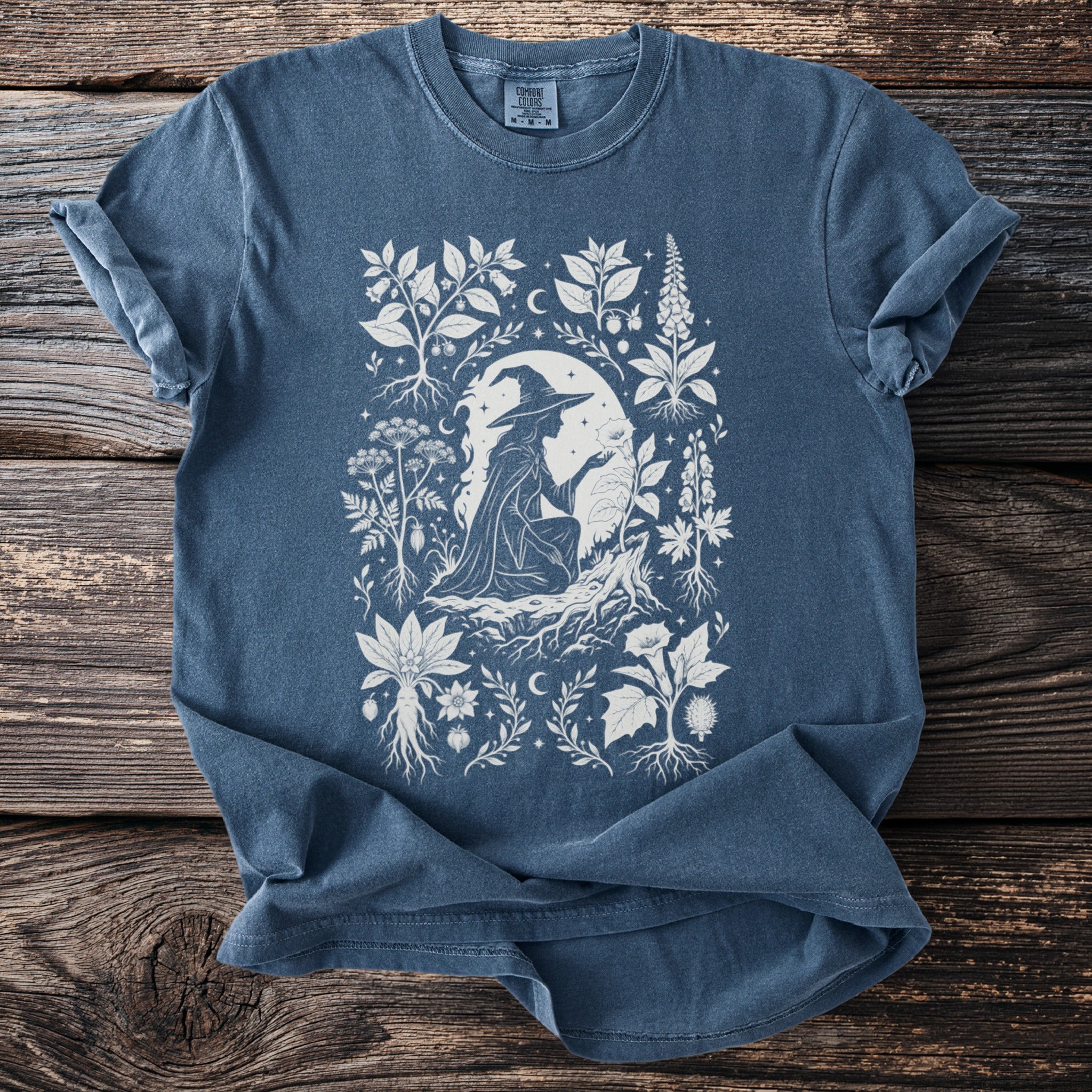 Blue t-shirt with white witch, plants and moon design.