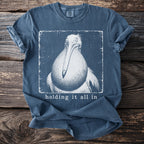 Blue t-shirt with a vintage-style drawing of a pelican and the text "holding it all in".