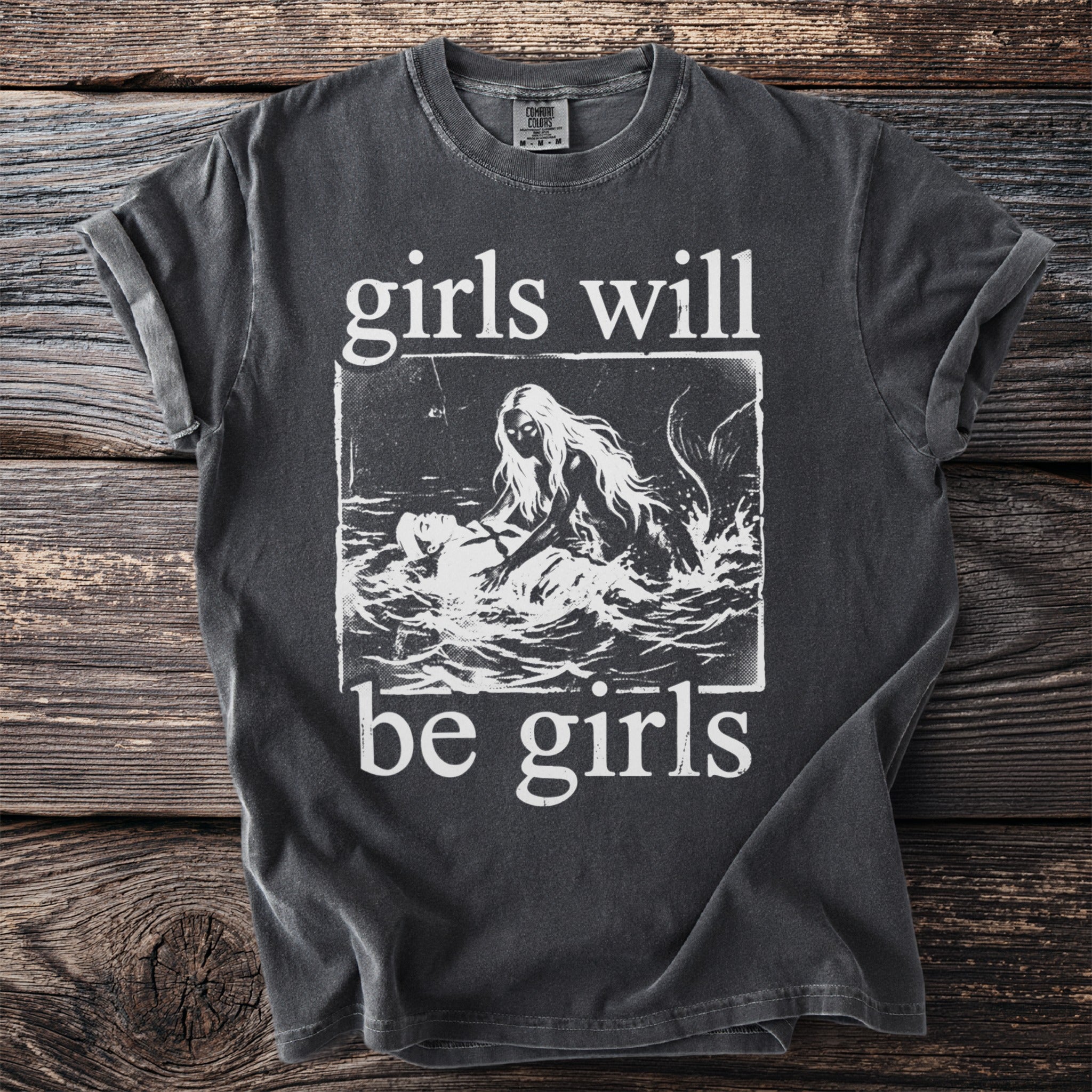 Dark grey t-shirt with white text "girls will be girls" and a siren pulling a man from water.