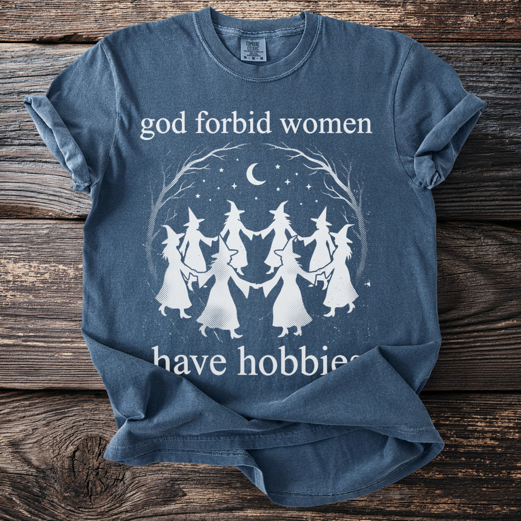 Blue t-shirt with "god forbid women have hobbies" and witch circle graphic.