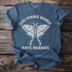 Blue t-shirt with white text "GOD FORBID WOMEN HAVE HOBBIES" and a moth graphic.