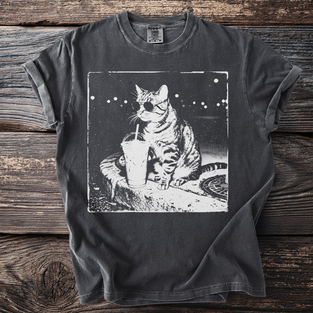 T-shirt with a graphic of a tabby cat wearing sunglasses and drinking from a straw.