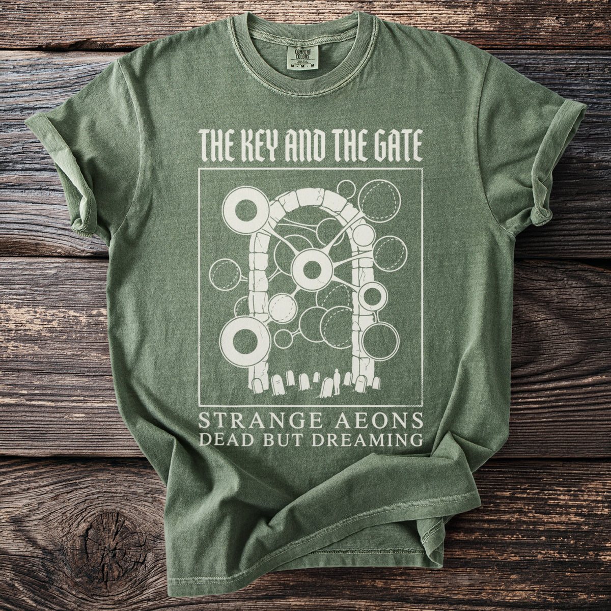Green t-shirt with "The Key and the Gate" graphic and text "Strange Aeons Dead But Dreaming".