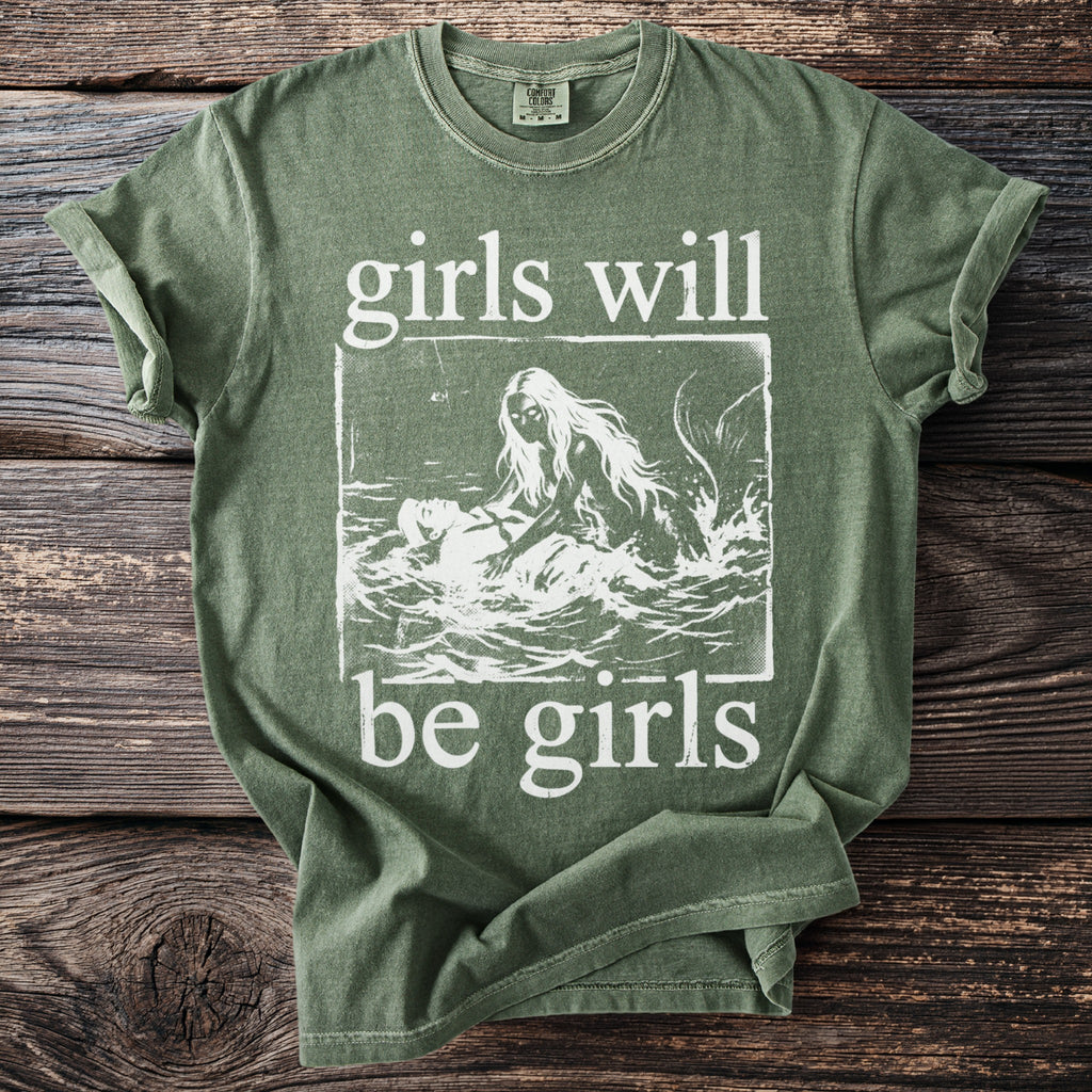 Green t-shirt with white graphic of mermaid pulling person into water and text "girls will be girls".
