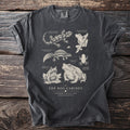 Dark grey t-shirt featuring "The Bog Cabinet" text and detailed illustrations of amphibians and a salamander.