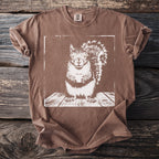 Brown t-shirt with a white graphic of a squirrel holding a cup on a wooden surface.