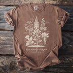 Brown t-shirt featuring vintage botanical illustrations of poisonous plants labeled "The Poison Garden."