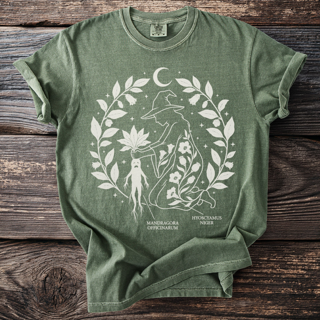 Green t-shirt with a white graphic of a witch, mandrake, and foliage.