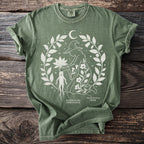 Green t-shirt with a white graphic of a witch, mandrake, and foliage.