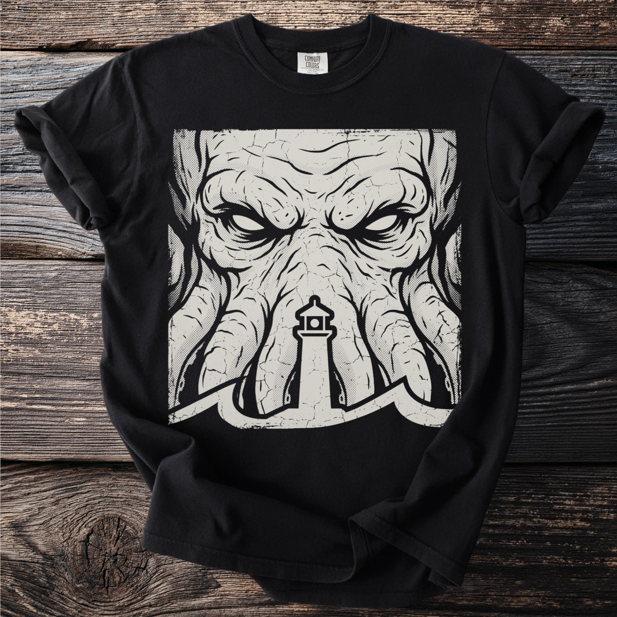 Black t-shirt with a distressed graphic of a monstrous face and a lighthouse in the waves.