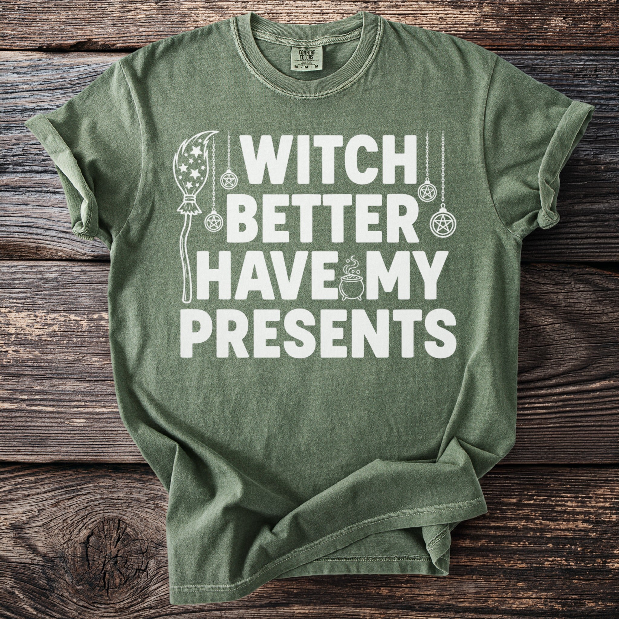 Green t-shirt with white text "Witch Better Have My Presents" and mystical graphics.