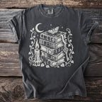 Dark grey t-shirt with white print of stacked books, candle, moth, moon, and key.