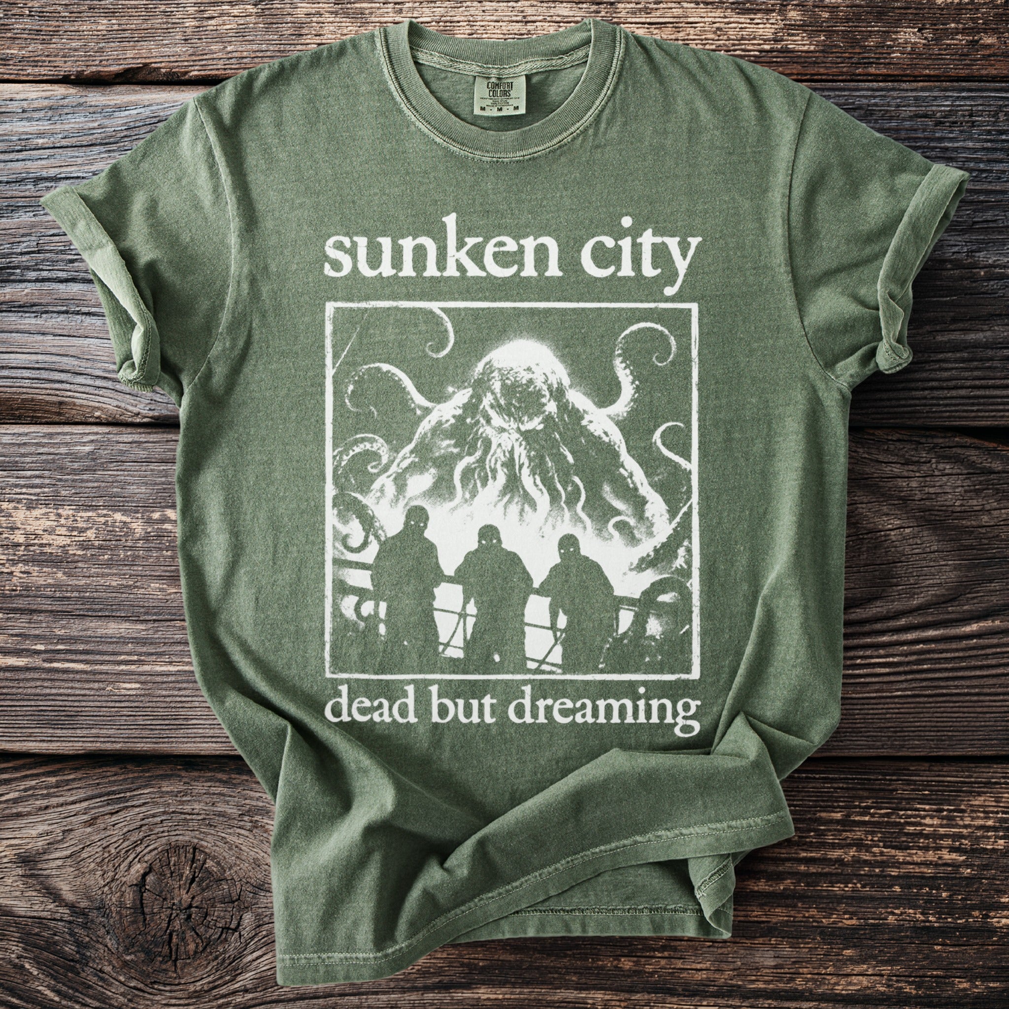 Green t-shirt with "Sunken City dead but dreaming" and a monster with tentacles.