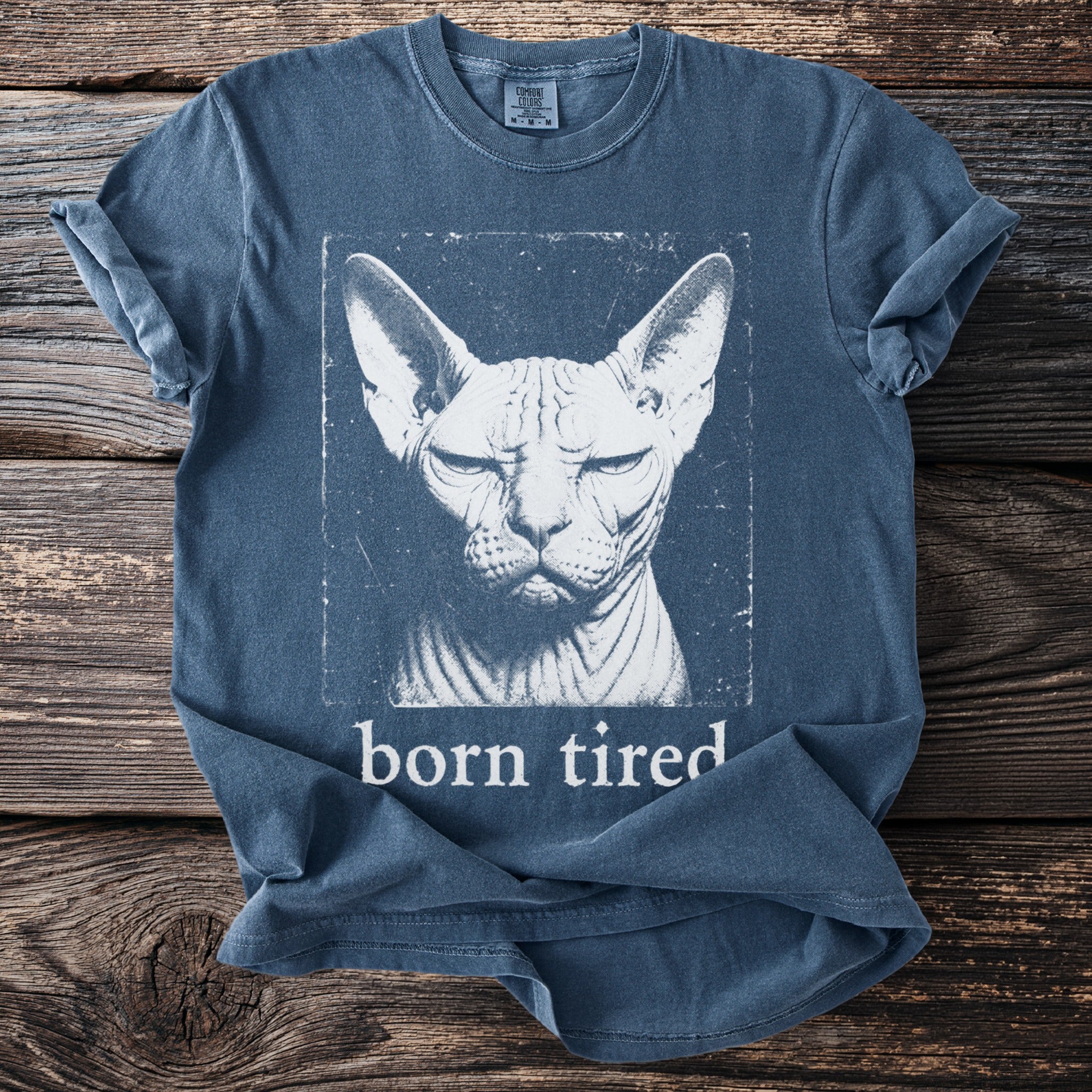 Blue t-shirt with a distressed graphic of a Sphynx cat and the text "born tired".
