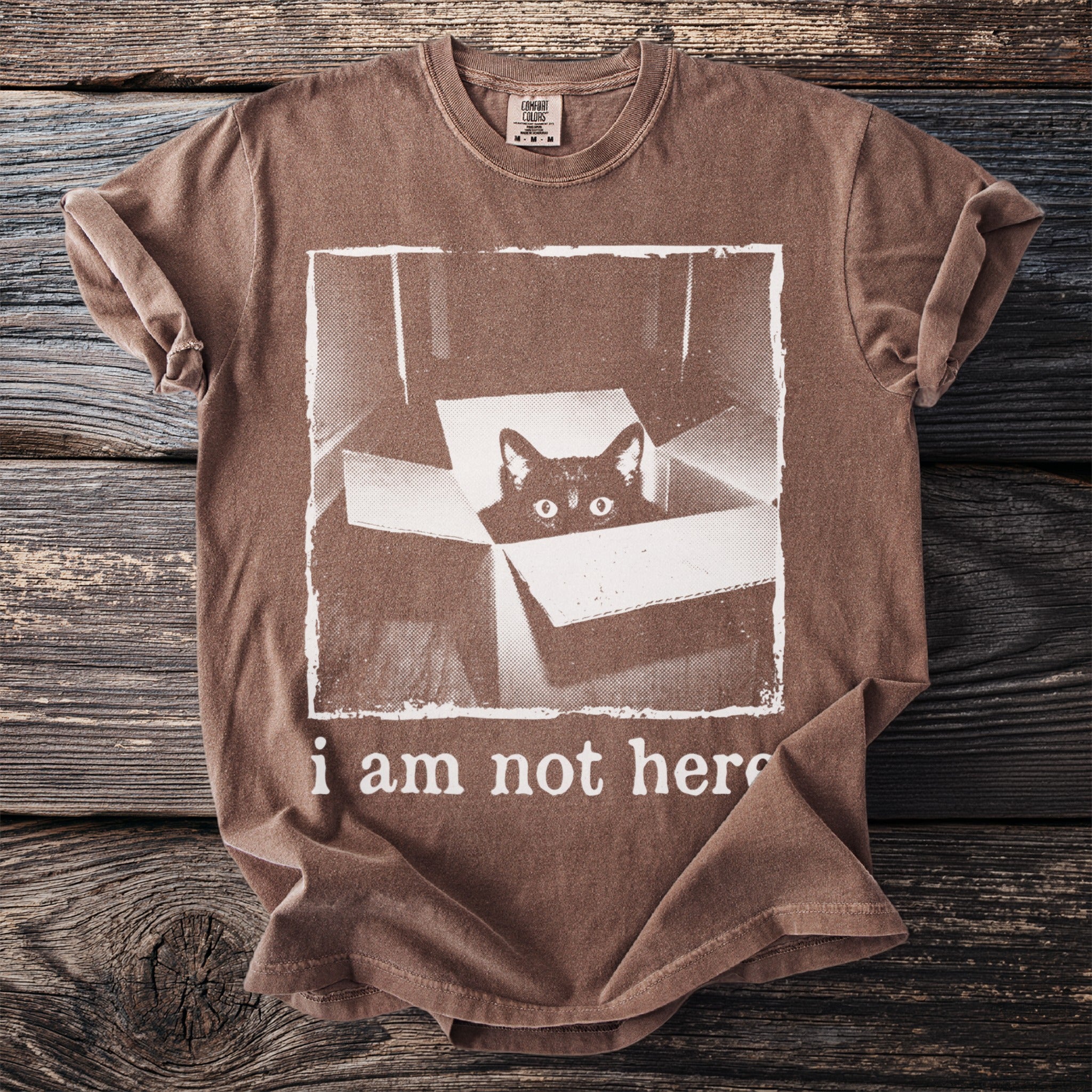 Brown t-shirt with a black cat peeking out of a box and text "i am not here".