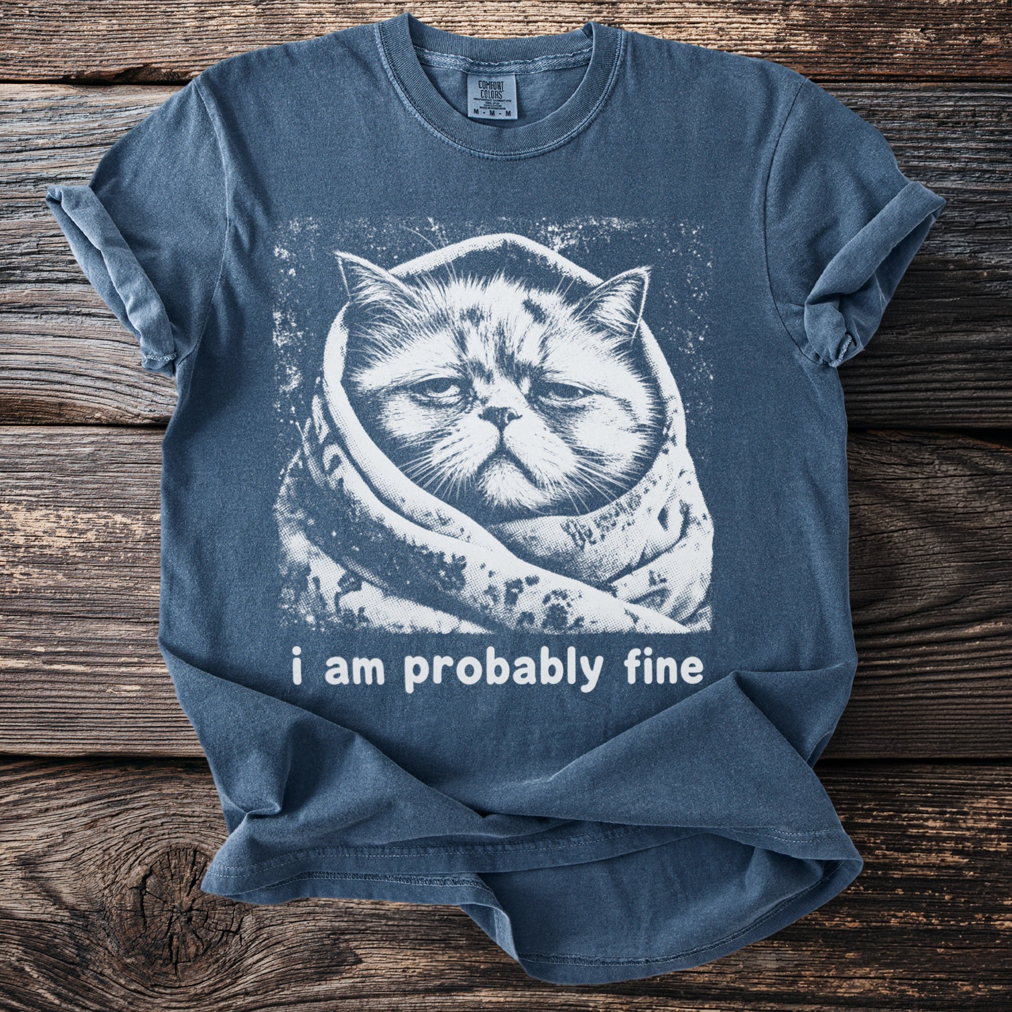 Blue t-shirt with a white graphic of a cat wrapped in a blanket, text reads "i am probably fine".