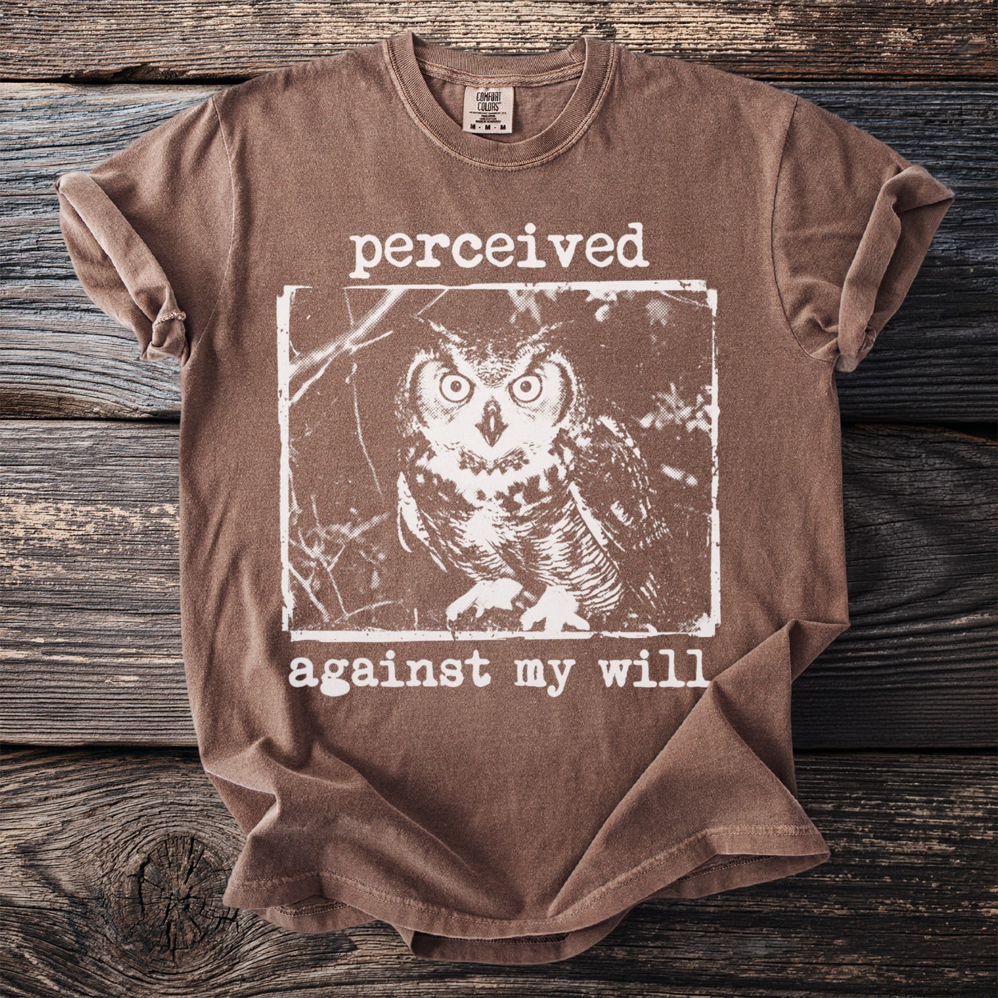 Brown t-shirt with graphic of an owl and text "perceived against my will".