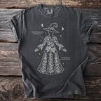 Dark t-shirt with white line art of a woman wearing a witch hat and adorned with poison hemlock and monkshood.