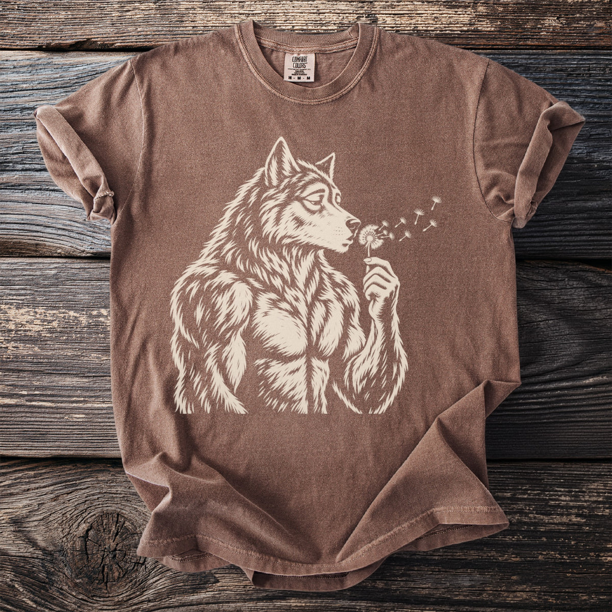 Brown t-shirt with cream graphic of a muscular werewolf blowing on dandelions.