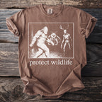 Brown t-shirt with Bigfoot, moth, and deer skull creatures and "protect wildlife" text.