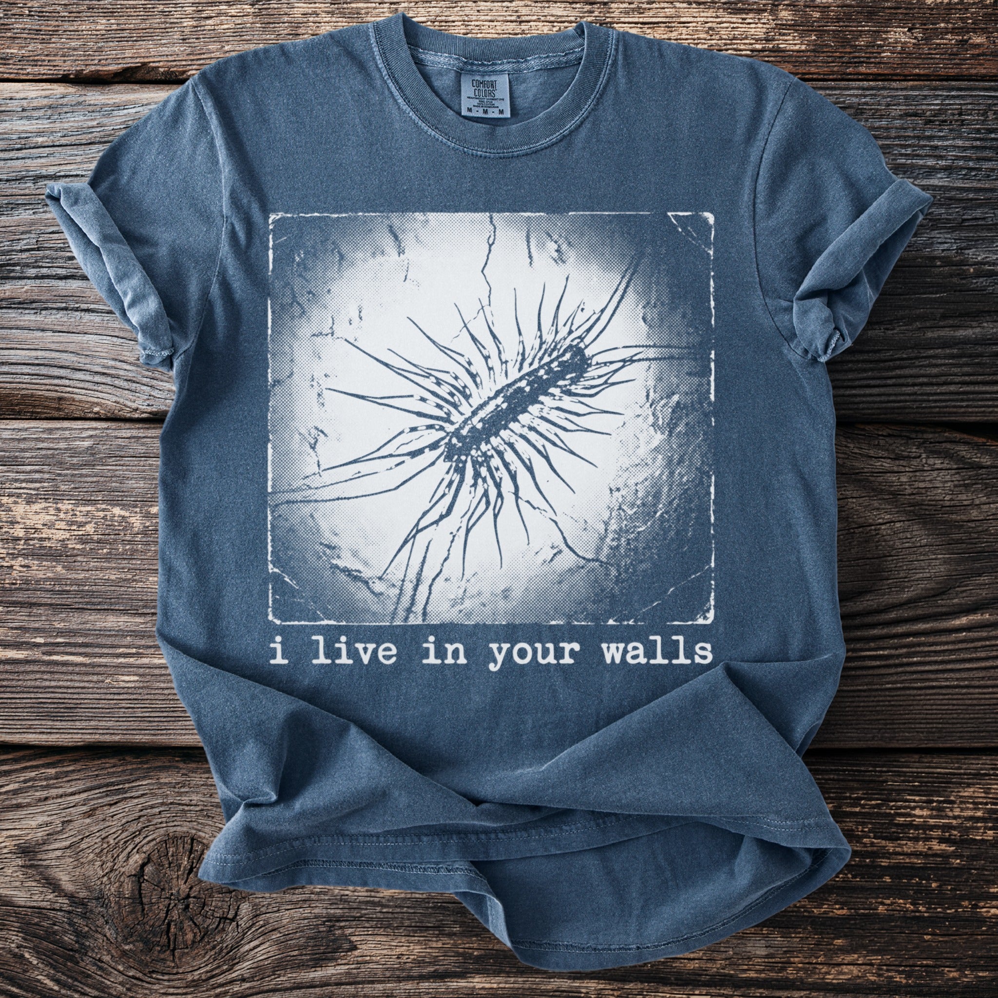 Blue t-shirt with image of a centipede and text "i live in your walls".