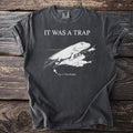 Charcoal t-shirt with IT WAS A TRAP and an engraved Tiktaalik, a lobe-finned fish, hauling itself onto rock, captioned Fig. 1: The Mistake.