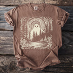 Brown t-shirt with a cream graphic of a ghost in a forest by a lake.
