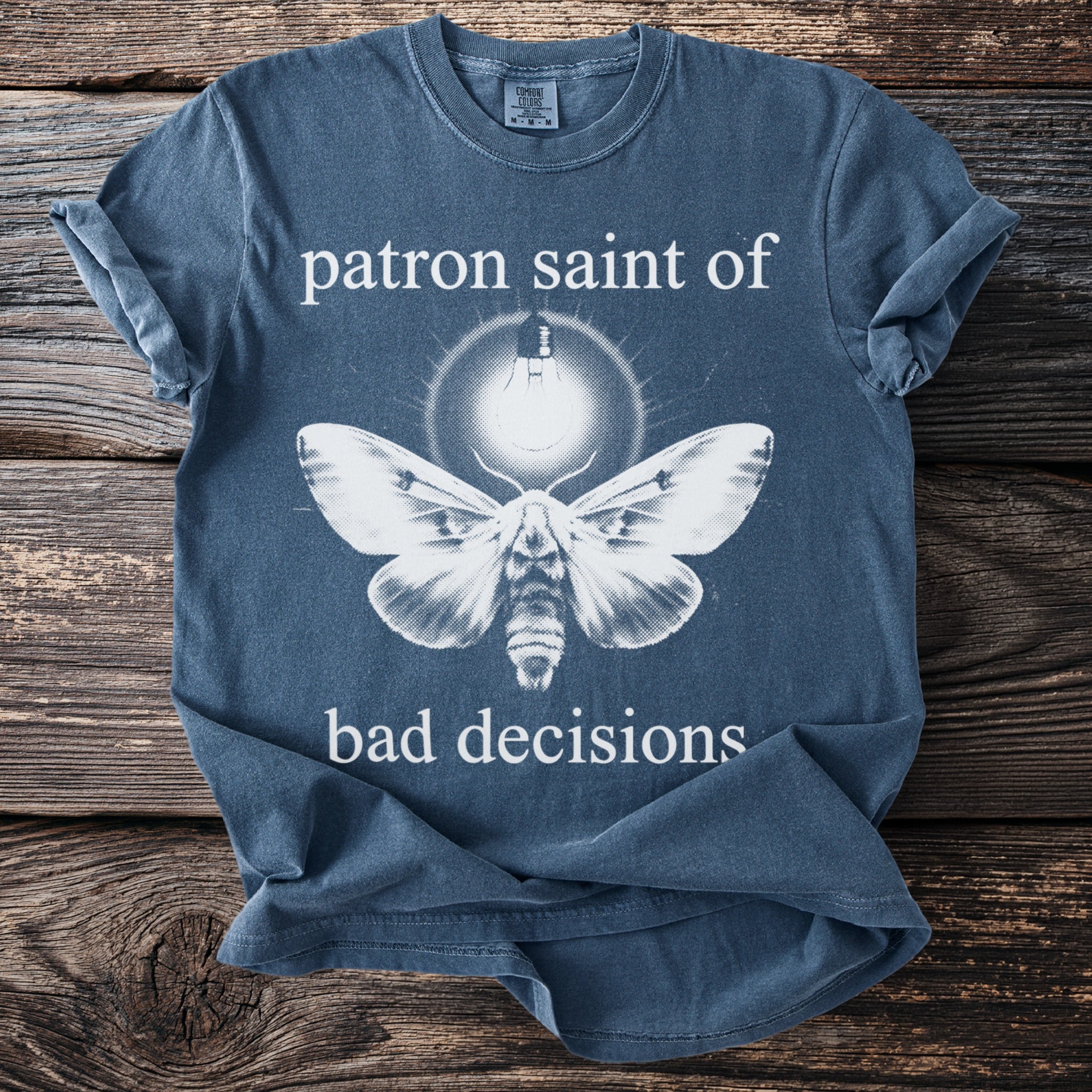 Blue t-shirt with moth illustration and text "patron saint of bad decisions".