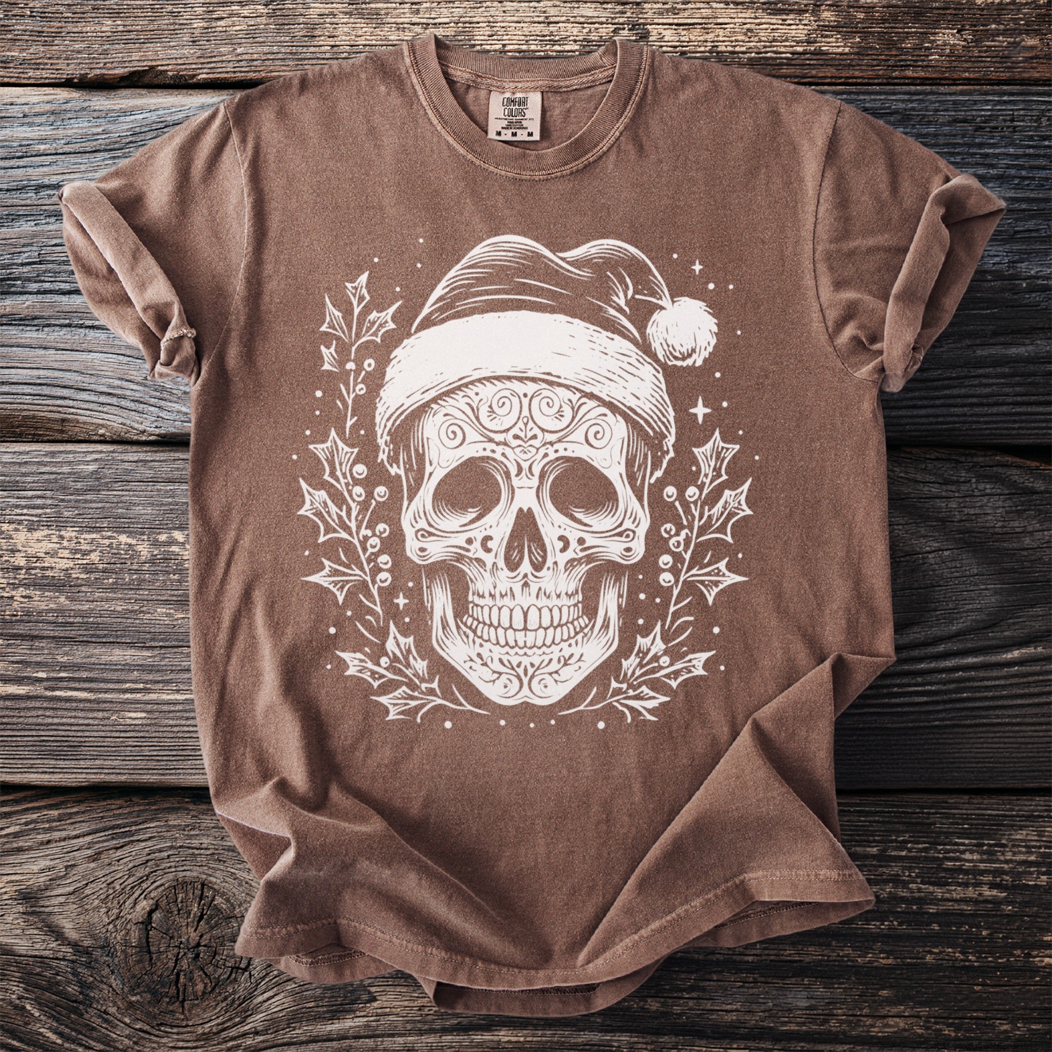 Brown t-shirt with white skull wearing Santa hat and holly design.