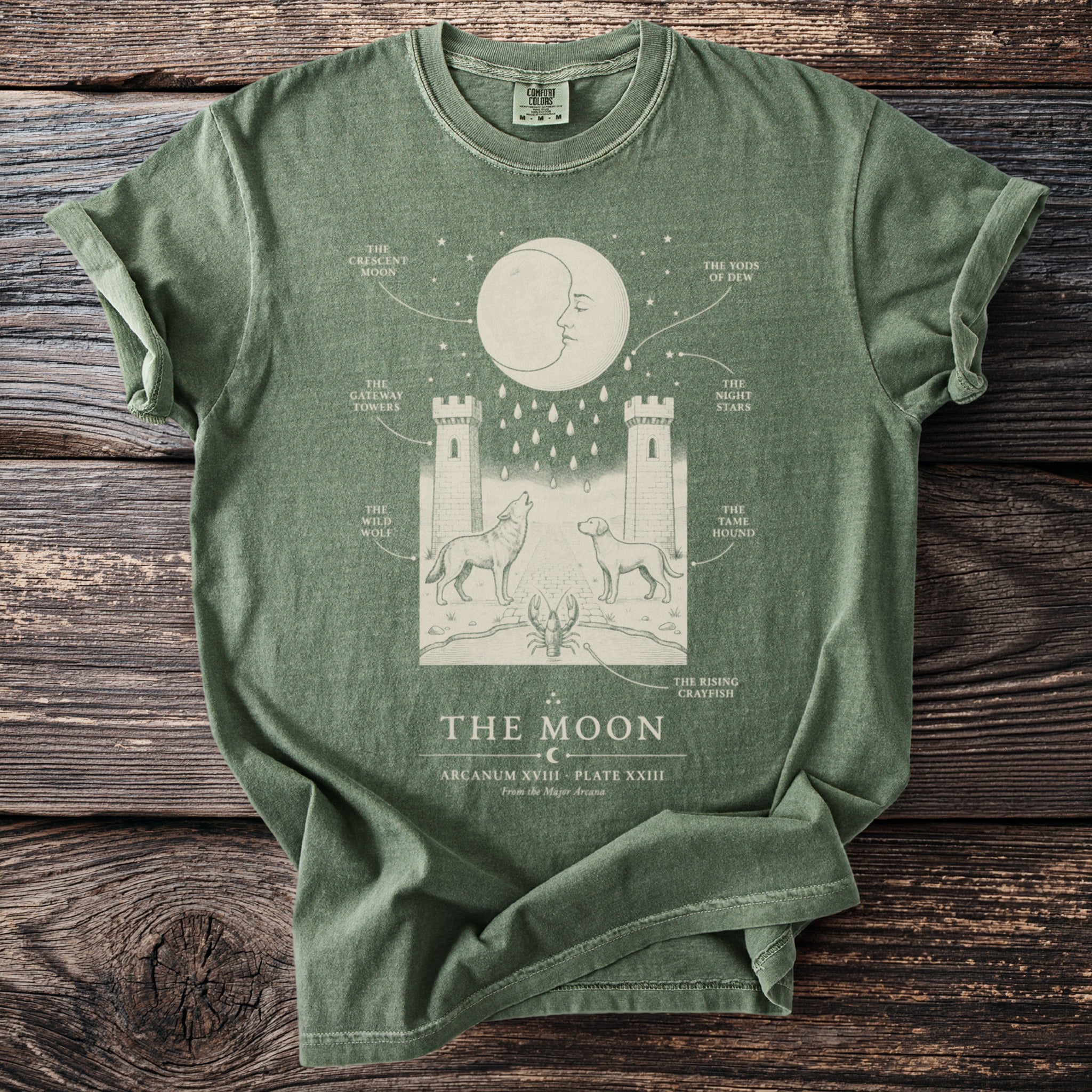 Green t-shirt with "The Moon" tarot card illustration featuring a crescent moon, towers, wolf, and dog.